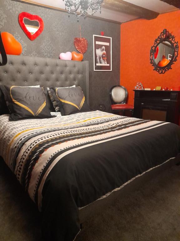 1 dormitorio con 1 cama con pared de color naranja en LOVE ROOM Le rouge et noir, en Barr