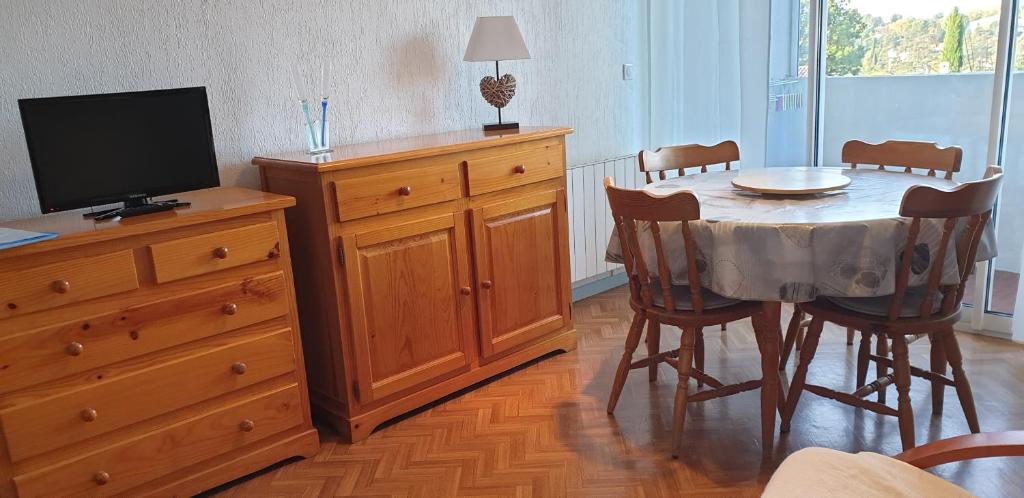 une salle à manger avec une table et une télévision sur une commode dans l'établissement Studio pour curistes et vacanciers, à Gréoux-les-Bains
