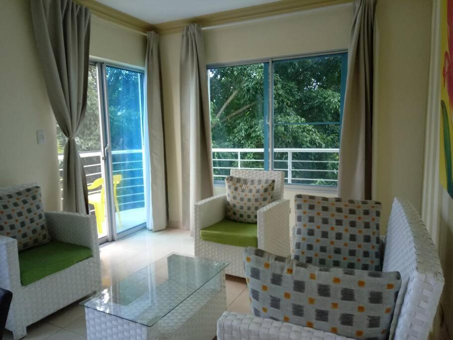 een woonkamer met stoelen en een tafel en ramen bij Condominio Rosario, Apto. 3-A, Playa in Boca Chica