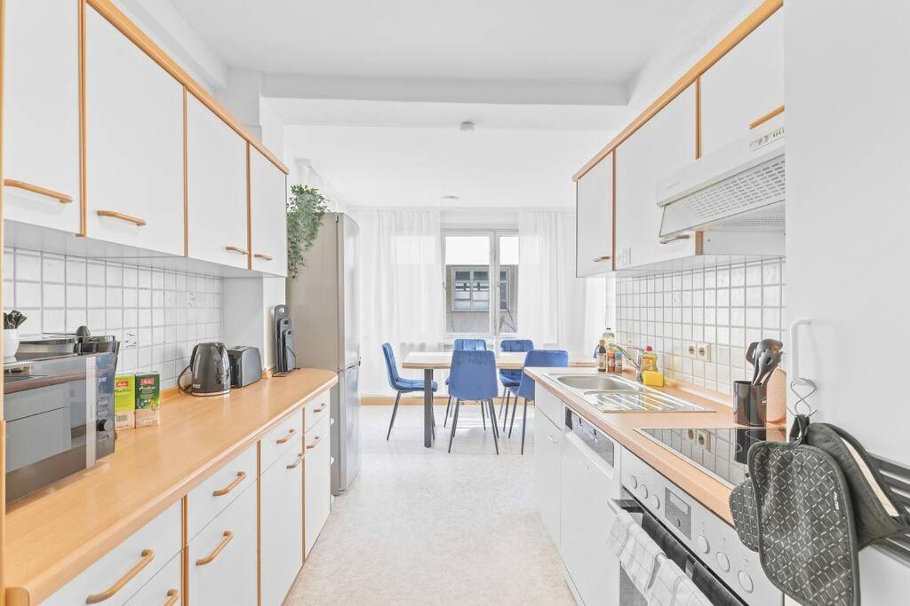 a kitchen with white cabinets and a table with blue chairs at ES03 Top Wohnung für 6 Personen in Oberesslingen