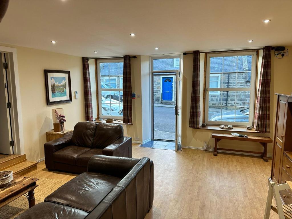 a living room with a couch and a chair and windows at The Old Chemist in Cullen