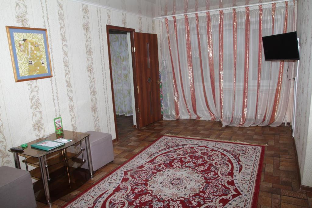 a living room with a rug and a table and a television at Монтана in Petropavlovsk