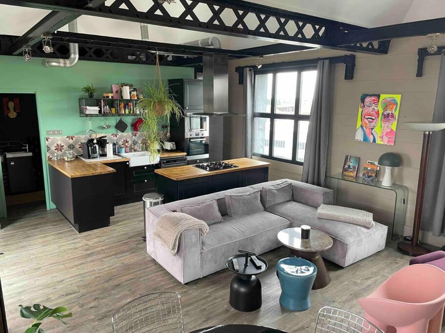 een woonkamer met een bank en een keuken bij Loft sur les toits de Roubaix in Roubaix