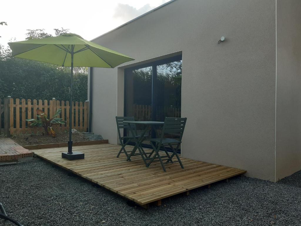 a patio with a table and chairs and an umbrella at Au ptit Manoir in Montbert