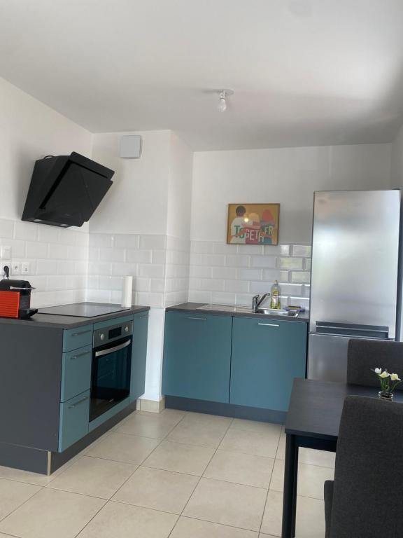 a kitchen with blue cabinets and a stainless steel refrigerator at Strasbourg appartement moderne in Strasbourg