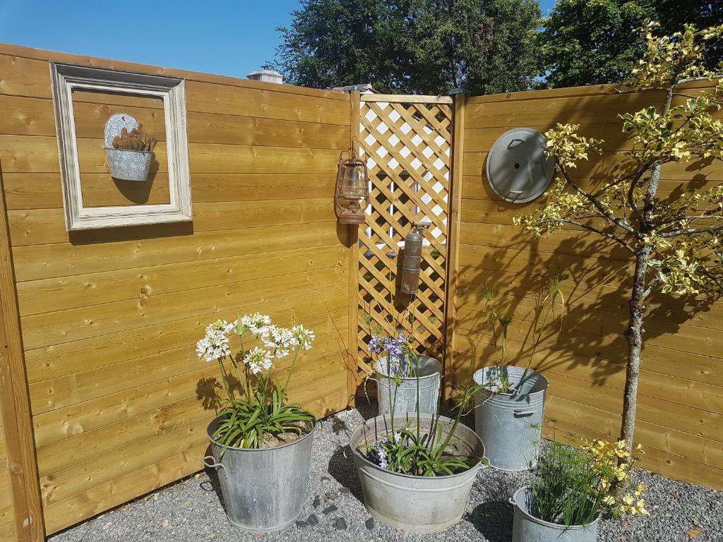 a wooden fence with three potted plants next to it at Au ptit Manoir in Montbert