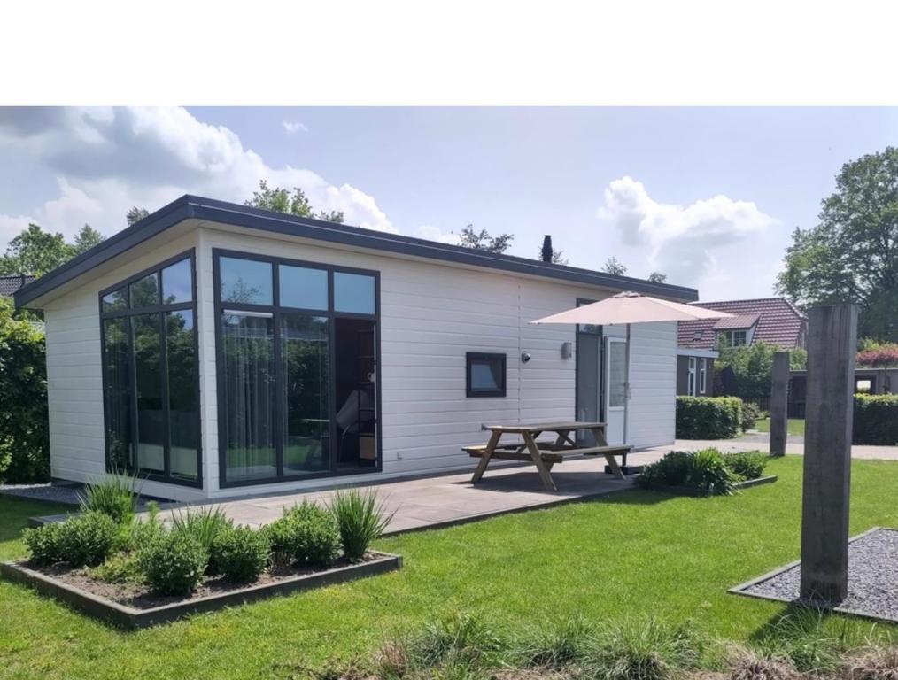 a small house with a picnic table and an umbrella at Knus chalet Heidebloem in Putten