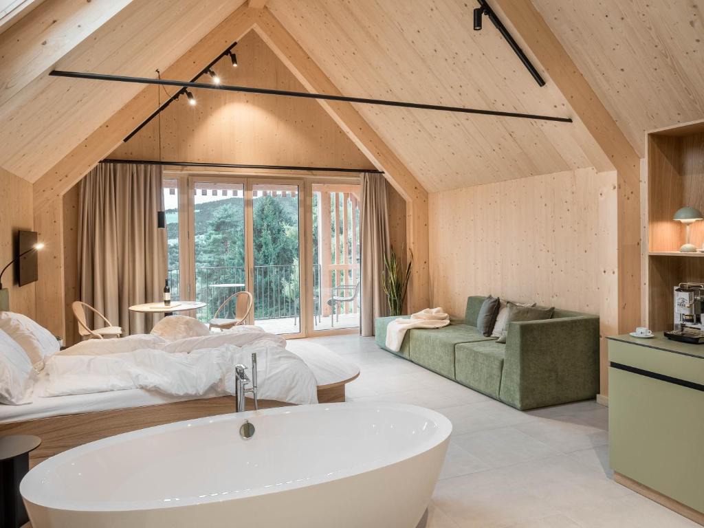 a bathroom with a bath tub and a bedroom at SCHILCHERLANDLEBEN - Hochgrail in Greisdorf