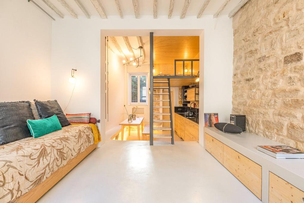 - un petit salon avec un canapé et un mur en pierre dans l'établissement Loft in Pernety, à Paris