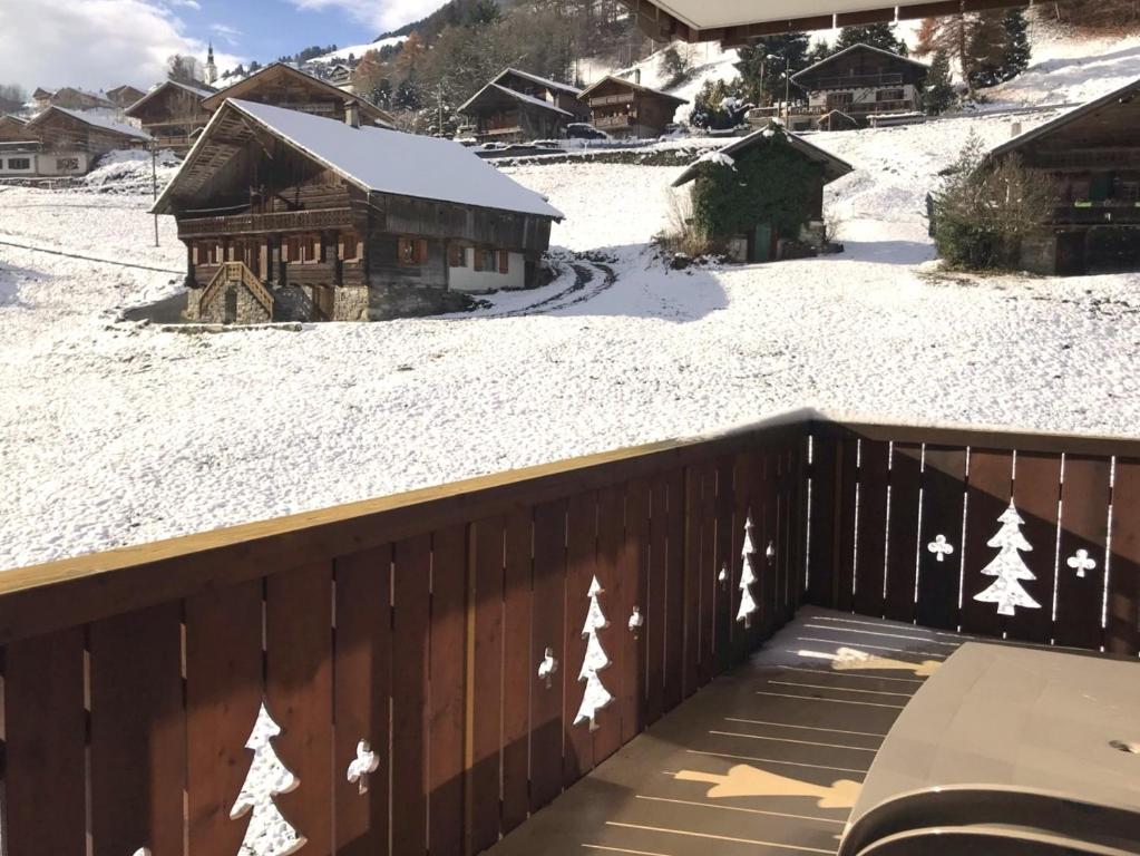 una terrazza in legno con neve per terra di Mountain River Luxury Apartment a Val-d'Illiez