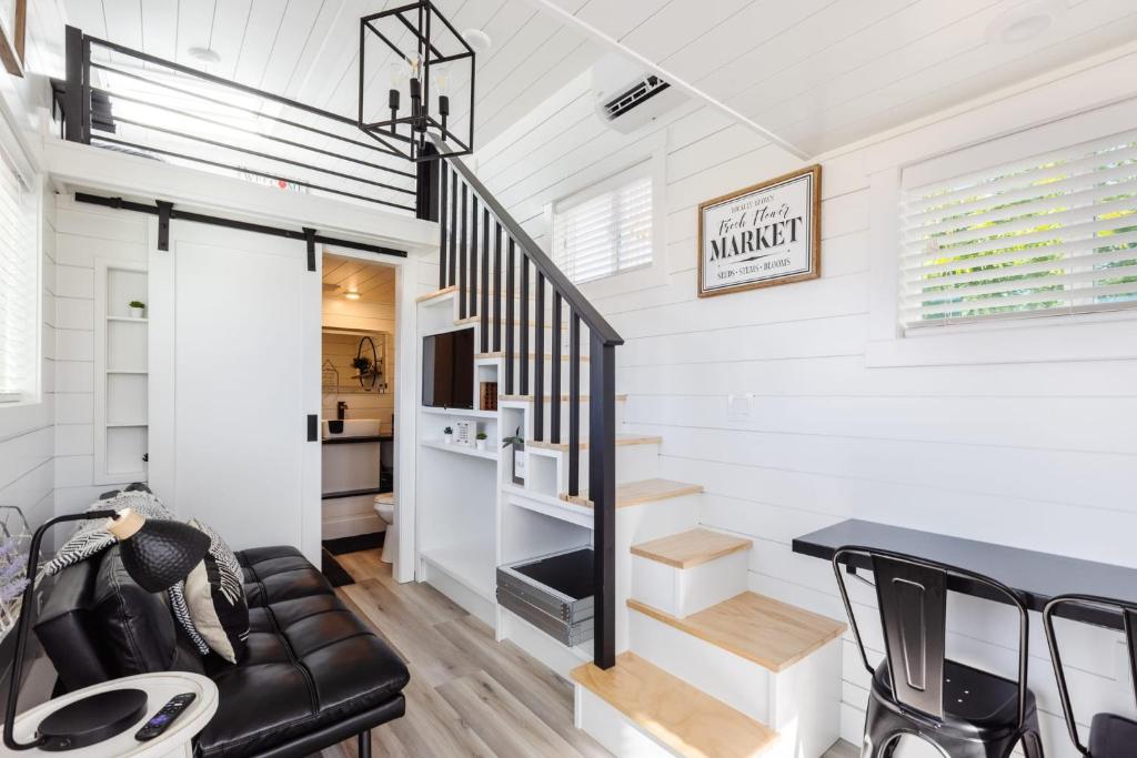 a living room with a staircase and a black leather couch at Zion Basecamp, Tiny Home Near National Park in Apple Valley