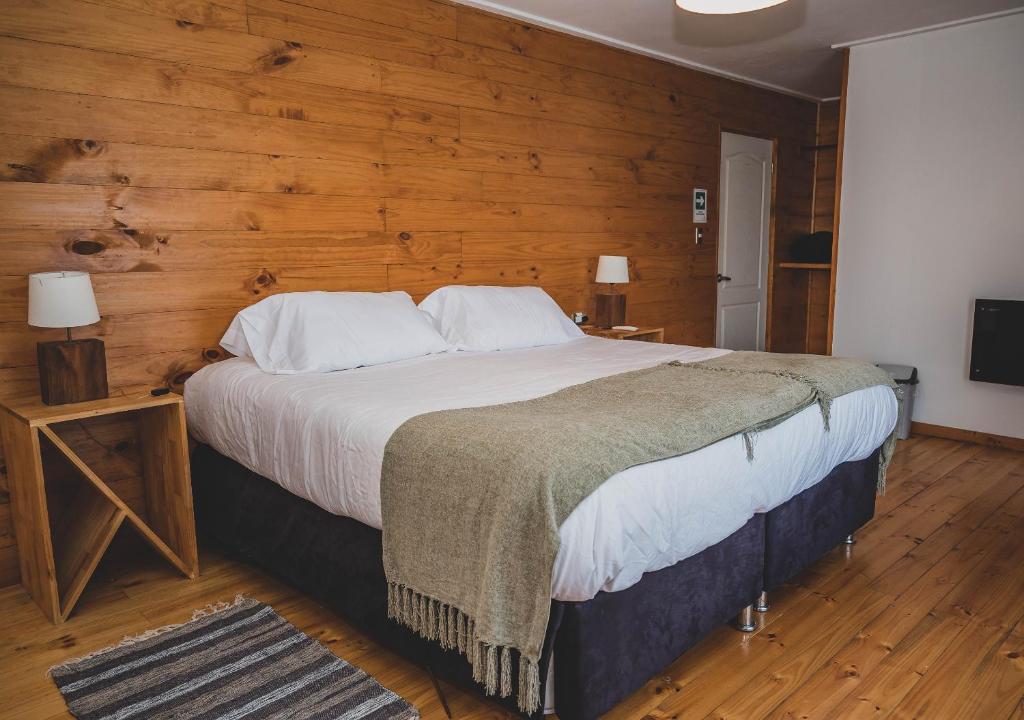 um quarto com uma cama grande e uma parede de madeira em Hotel Puerto Madera by DOT Boutique em Pelluhue