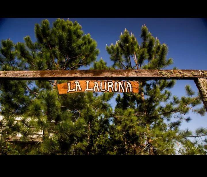 a wooden sign that reads la la latrine in front of trees at La Laurina Casa de Campo Hotel/Hospedaje in Villa Lonca