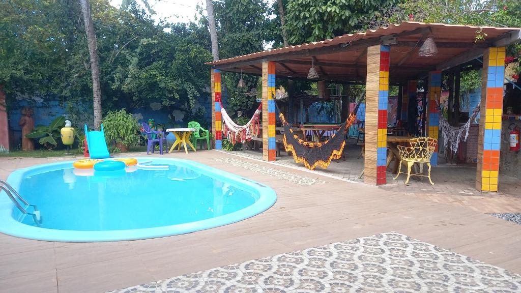 a swimming pool in a backyard with a pavilion at Pousada Casa Colorida in Porto De Galinhas