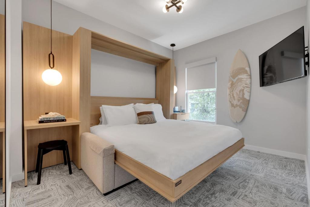 Schlafzimmer mit einem Bett, einem Schreibtisch und einem TV in der Unterkunft The St Laurent Guest Rooms in Asbury Park