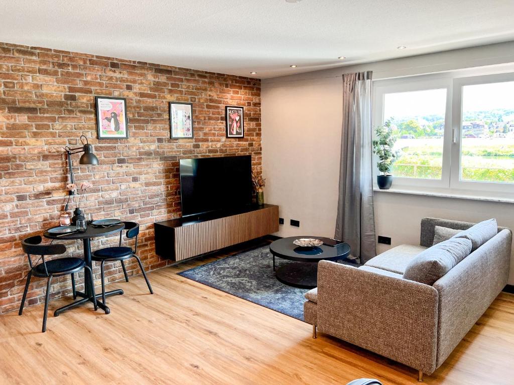 un soggiorno con divano e muro di mattoni di Red Rock Apartments - mit Parkplatz, Küche und Netflix a Treviri
