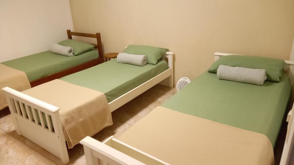 3 camas en una habitación con sábanas verdes en Los Cerezos de Ema en Puerto Iguazú