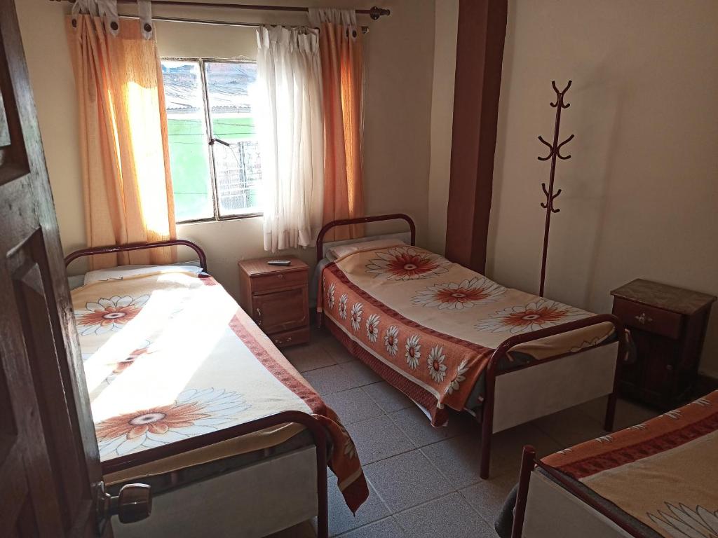 a bedroom with two beds and a window at HOTEL ANAHÍ in Chulumani