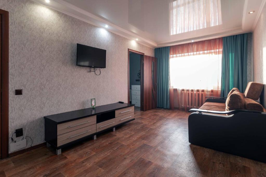 a living room with a couch and a tv on the wall at Паттайя in Petropavlovsk