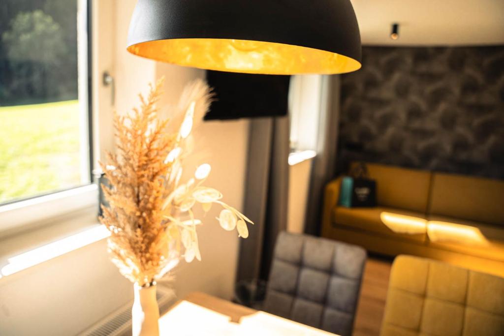 una lámpara en una mesa con un jarrón de flores en Maurig Appartements, en Elbigenalp