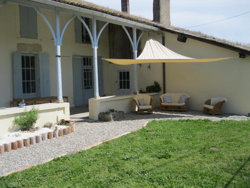 ein Haus mit einer Terrasse mit einem großen Sonnenschirm in der Unterkunft La Metairie des Ducs in Sainte-Colombe-de-Duras