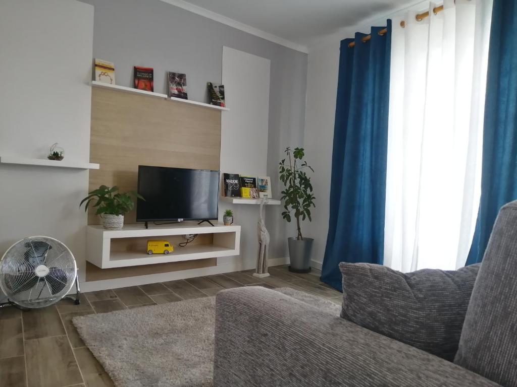 ein Wohnzimmer mit einem Flachbild-TV und blauen Vorhängen in der Unterkunft Apartamento T1 46B in Lagoa