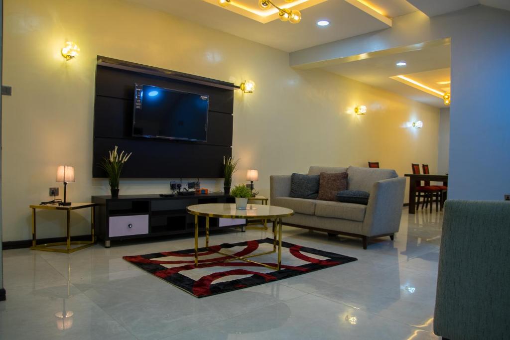 a living room with a couch and a table and a tv at Lake Luxury Homes in Ibadan