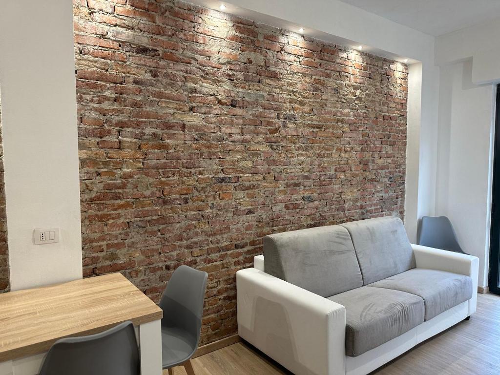 pared de ladrillo en una habitación con sofá y mesa en F&F Appartments, en Iglesias