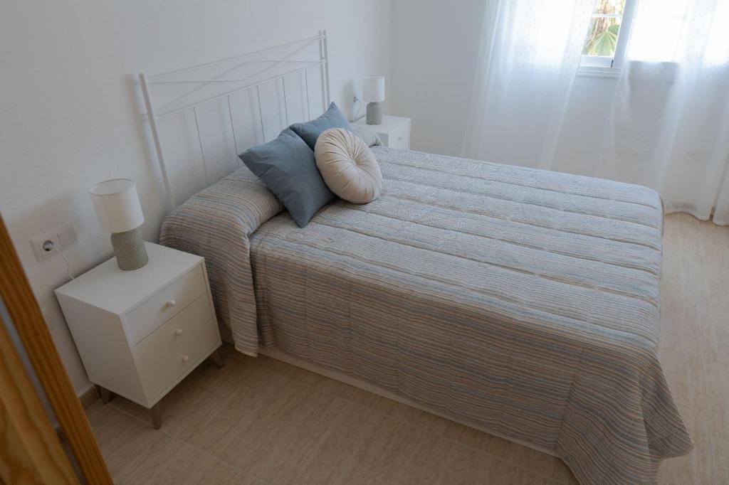 a white bedroom with a bed with blue pillows at Casa Trastévere in San Juan de los Terreros