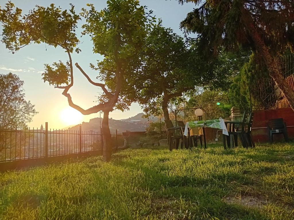 een tafel en stoelen in het gras met de zonsondergang op de achtergrond bij Casa L'agrumeto in Ventimiglia