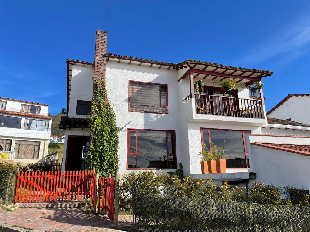 una casa blanca con una valla roja delante de ella en Caro Ruiz Hospedaje, en Guatavita