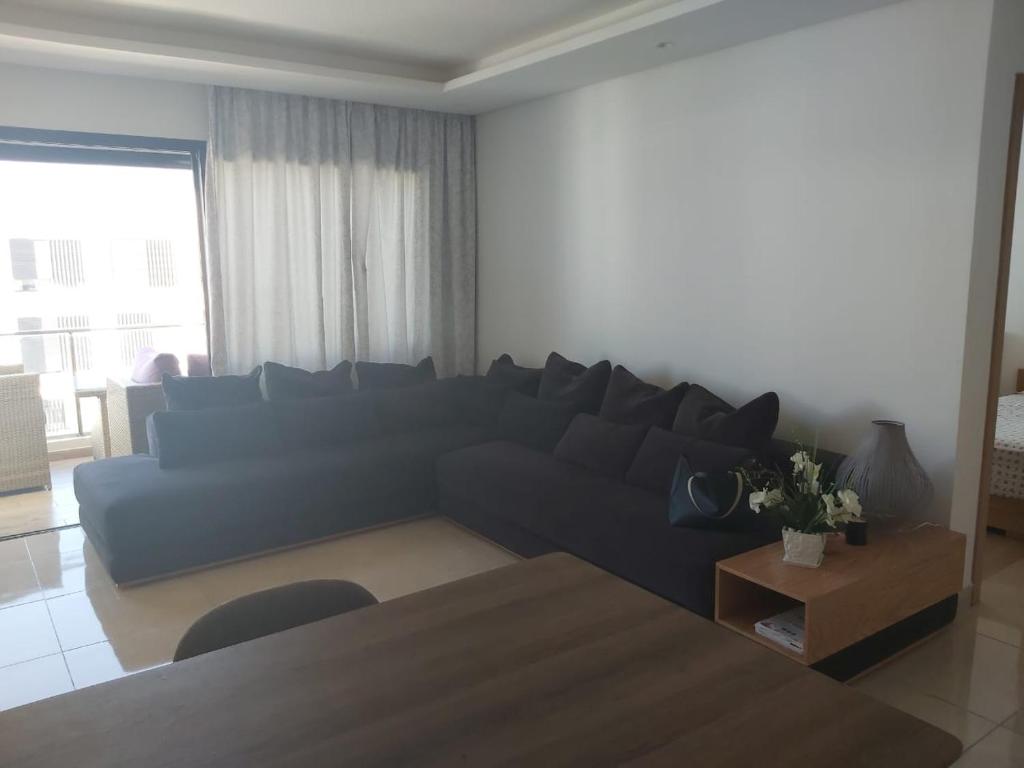 ein Wohnzimmer mit einem blauen Sofa und einem Tisch in der Unterkunft Prestigia plage des nations bouknadel salé in Salé