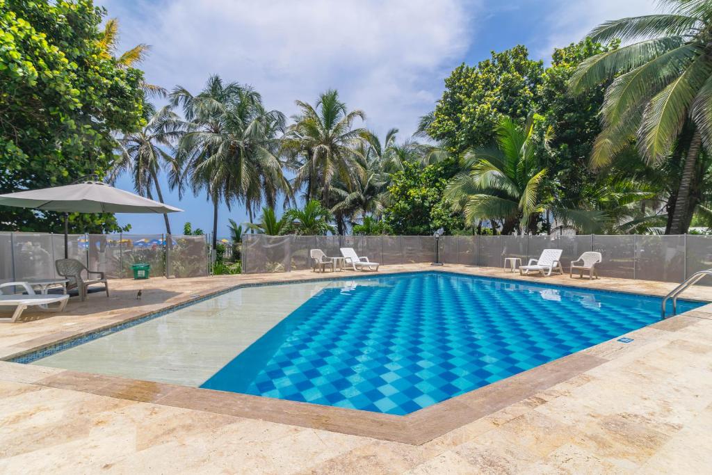 卡塔赫纳Apartamento Unik Cartagena Edificio Faro Tequendama的带椅子和棕榈树的游泳池