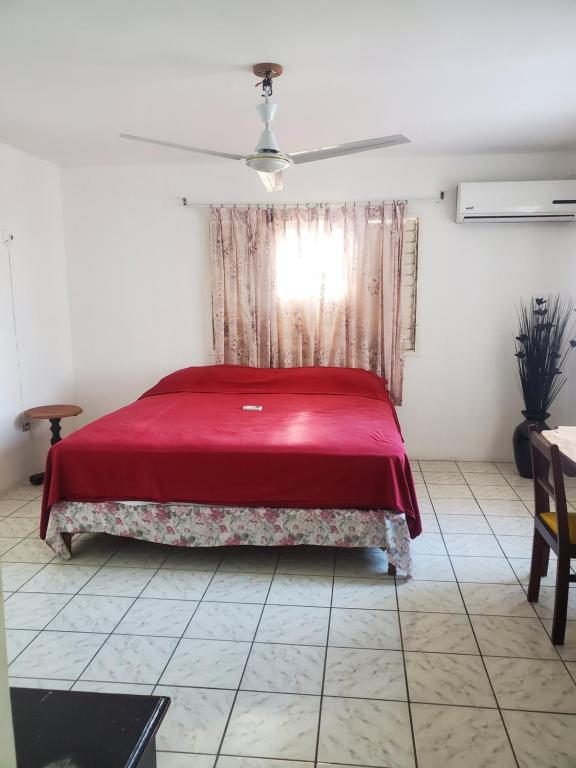 a bedroom with a red bed and a window at Evelin's On The Beach in Montego Bay