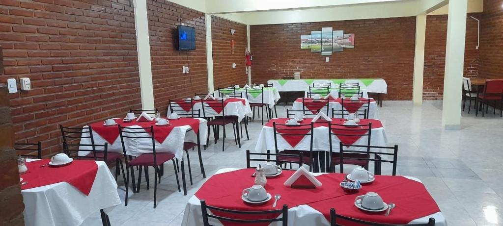 un comedor con mesas y sillas rojas y blancas en Hotel Sol en Termas de Río Hondo