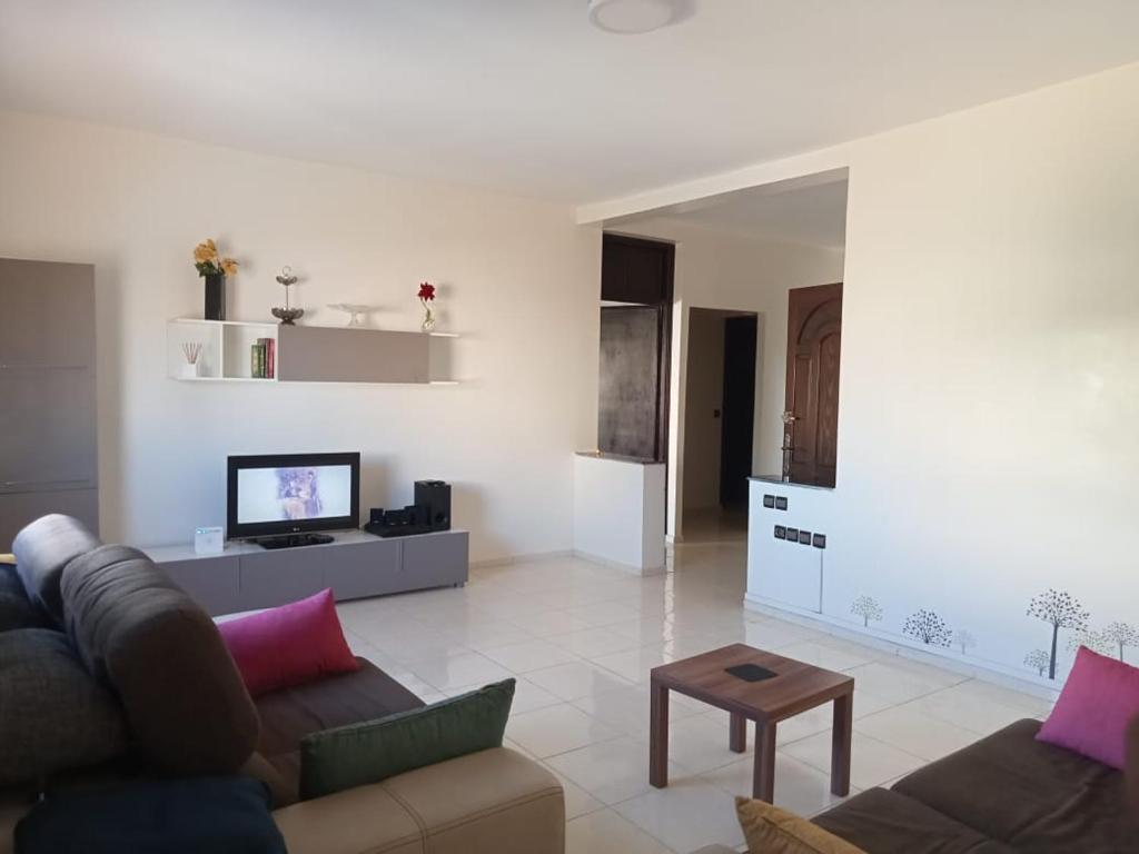 ein Wohnzimmer mit einem Sofa und einem TV in der Unterkunft Maison indépendante 100m2 à Témara centre in Temara