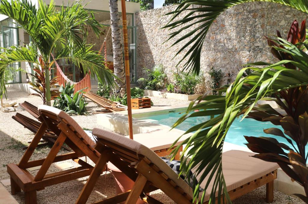 un patio con 2 sillas, una mesa y una piscina en Nuik Casa Tropical, en Mérida