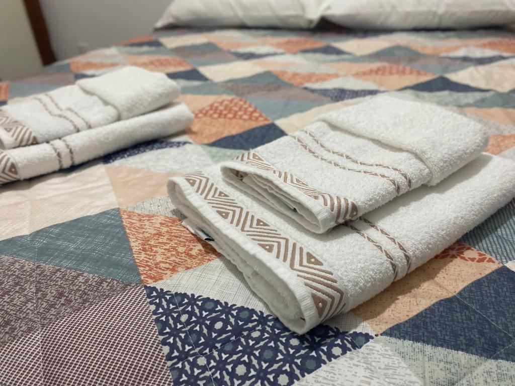 two towels sitting on top of a quilt on a bed at APTO - Espaço Village Completo - 2Q in Vitória
