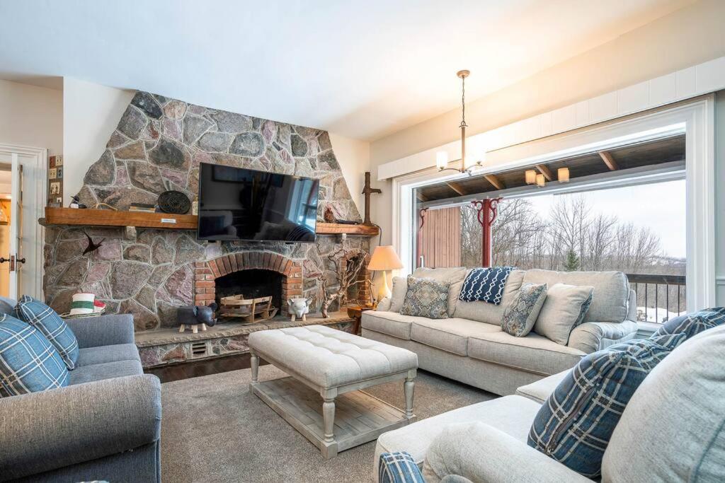 a living room with a stone fireplace and a tv at Sundance of Blantyre Lodge w Hot Tub & Sauna House in Walter's Falls