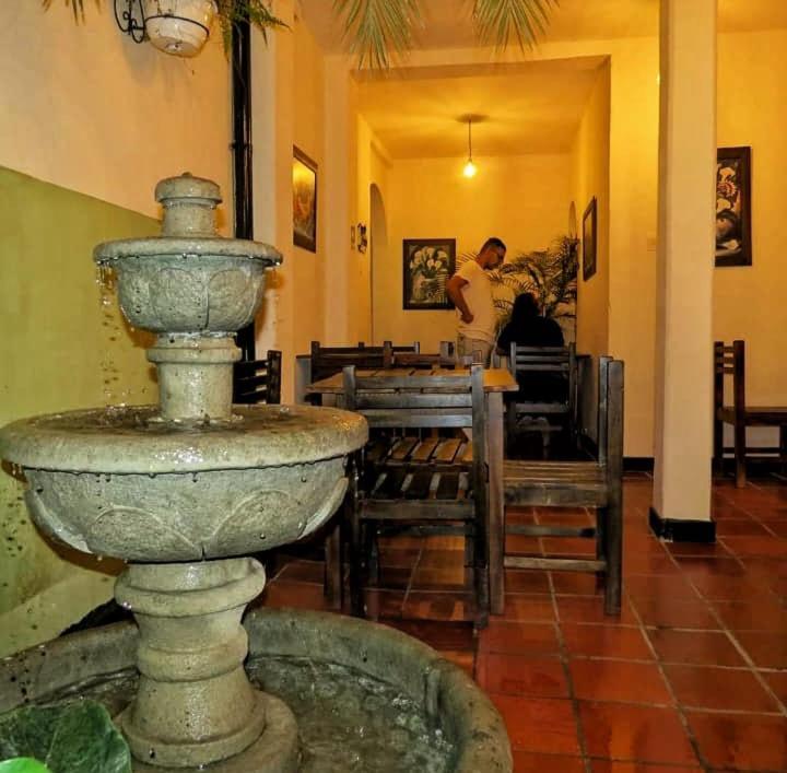 una fuente de piedra en un restaurante con un hombre al fondo en Hostal Belén en Popayán