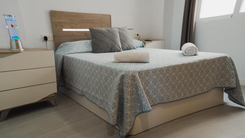 um quarto com uma cama com um cobertor e uma cómoda em apartaluxdenia em Denia
