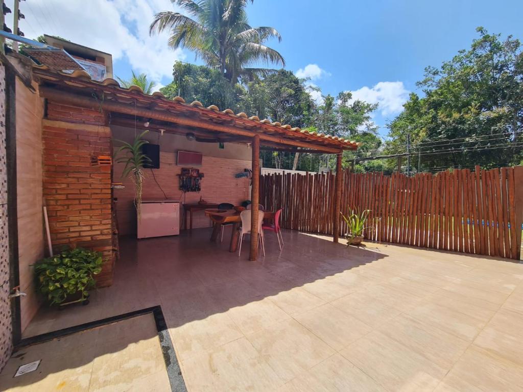 un patio con una mesa y una valla de madera en CASA do BRUNO ARRAIAL D'AJUDA, en Arraial d'Ajuda