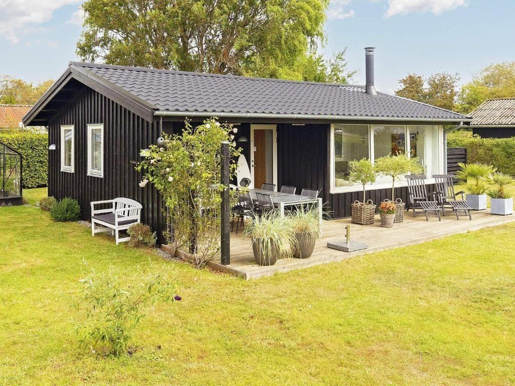 una piccola casa nera con una terrazza in legno in un cortile di Holiday home Karrebæksminde IX a Karrebæksminde