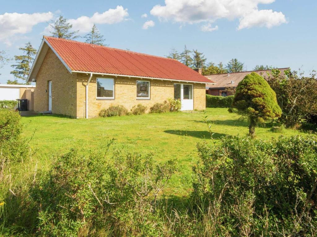 una casa con un tetto rosso su un campo verde di 5 person holiday home in Skjern-By Traum a Skjern