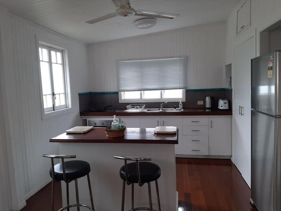 a kitchen with a refrigerator and two bar stools at Wangan Tropical Getaway 