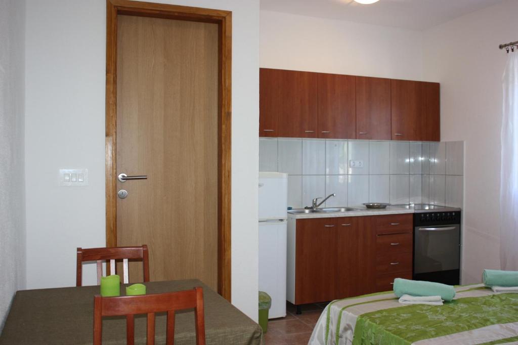 een kleine keuken met een tafel en stoelen en een deur bij Studio Apartment Lenka in Milna