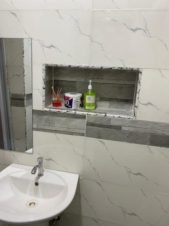 a white bathroom with a sink and a mirror at Melford Homes in Lagos