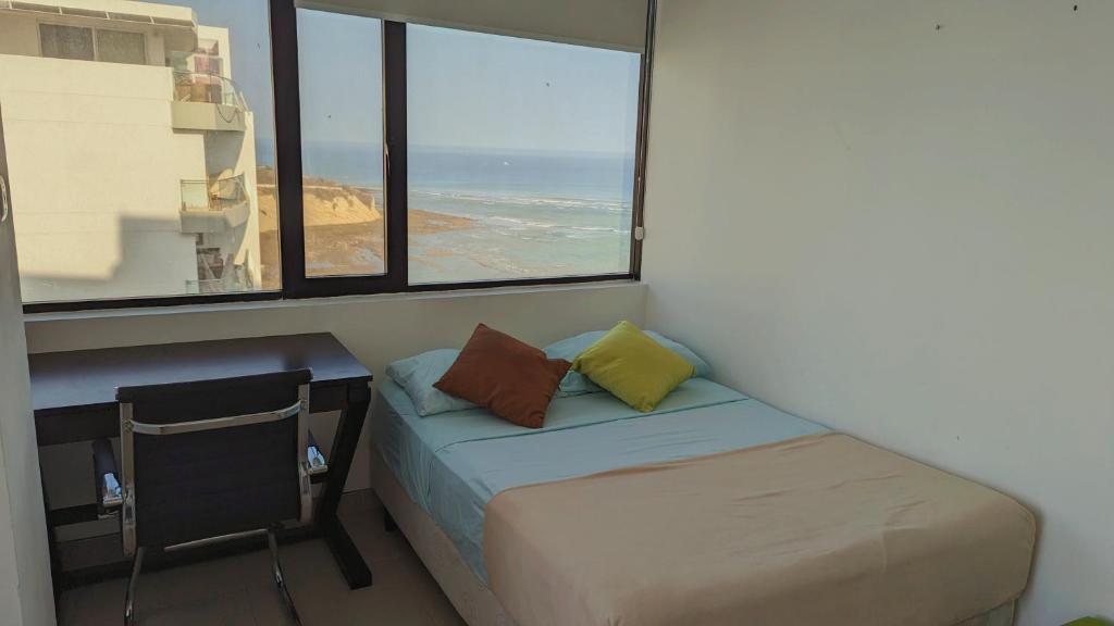 a bed and a desk in a room with a window at Departamento vista al mar en Manta Poseidon in Manta