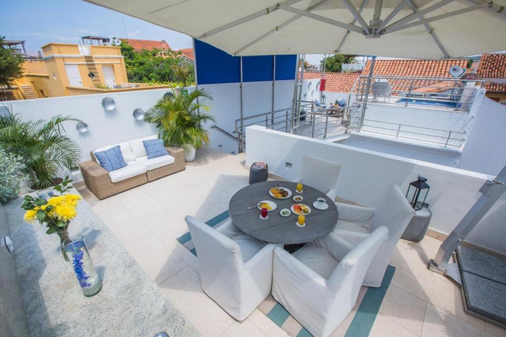 un patio con mesa, sillas y sombrilla en Casa Estilo Colonial 7LC-N En El Centro Histórico Con Piscina Aire Acondicionado y Wifi en Cartagena de Indias
