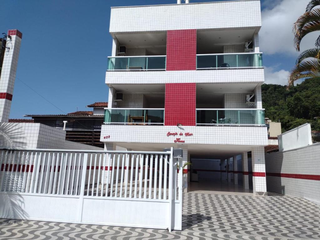 a red and white building with a white fence at Apartamento Cereja do Mar in Ubatuba